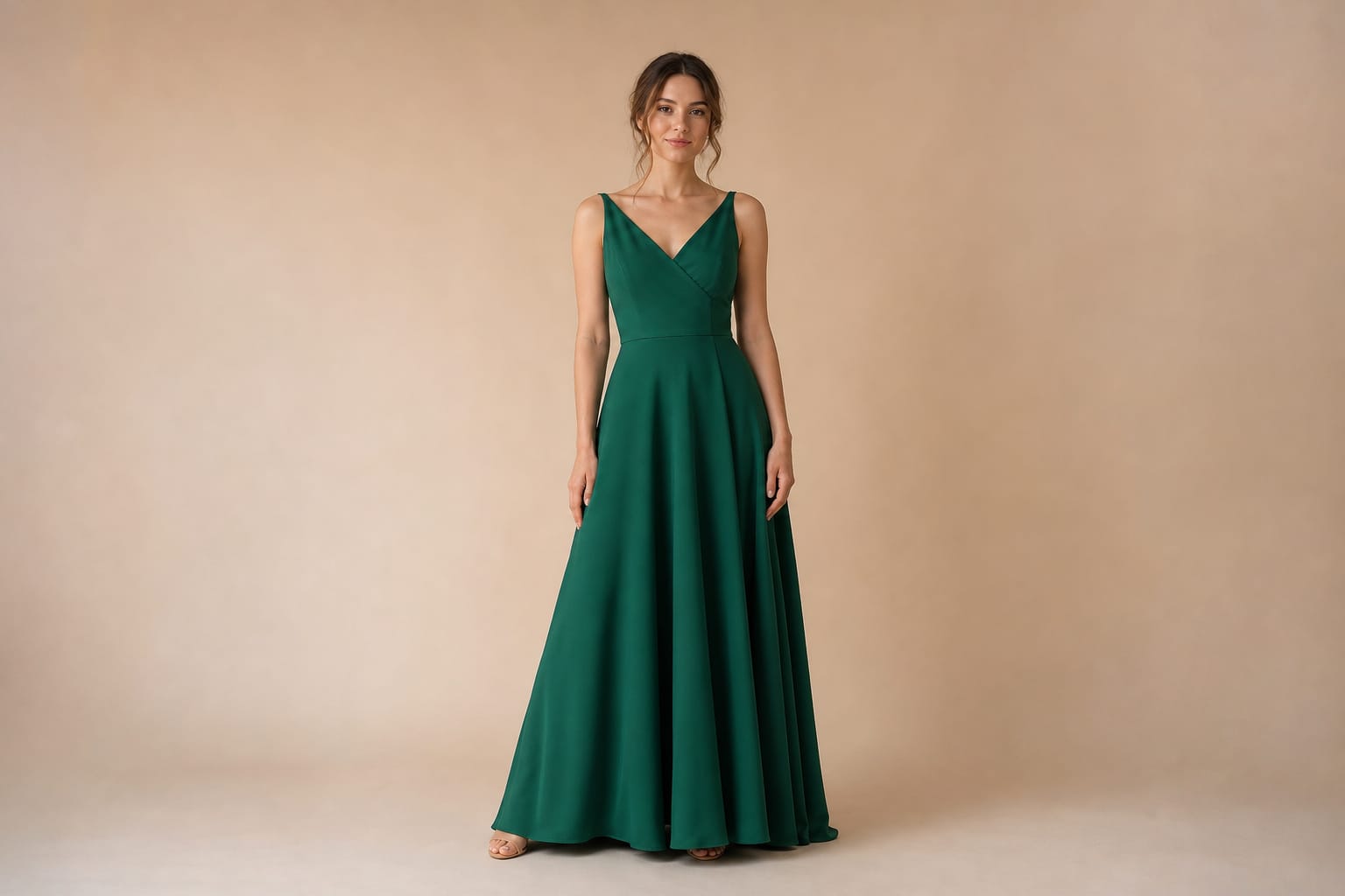 Woman in an emerald A-line evening gown standing in a studio, the hem touching the floor