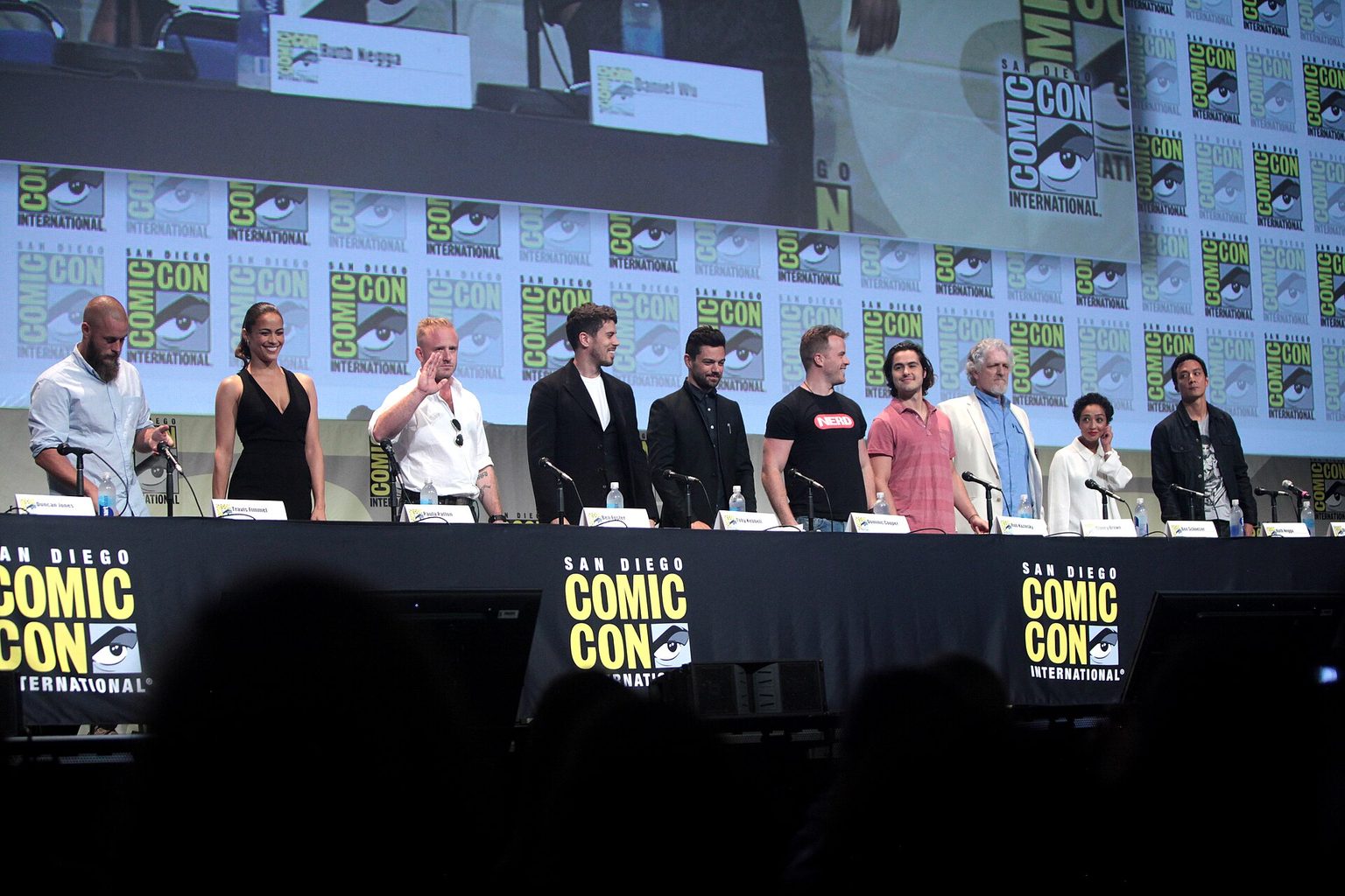 The Warcraft cast standing behind a long table on the Comic-Con stage in 2015