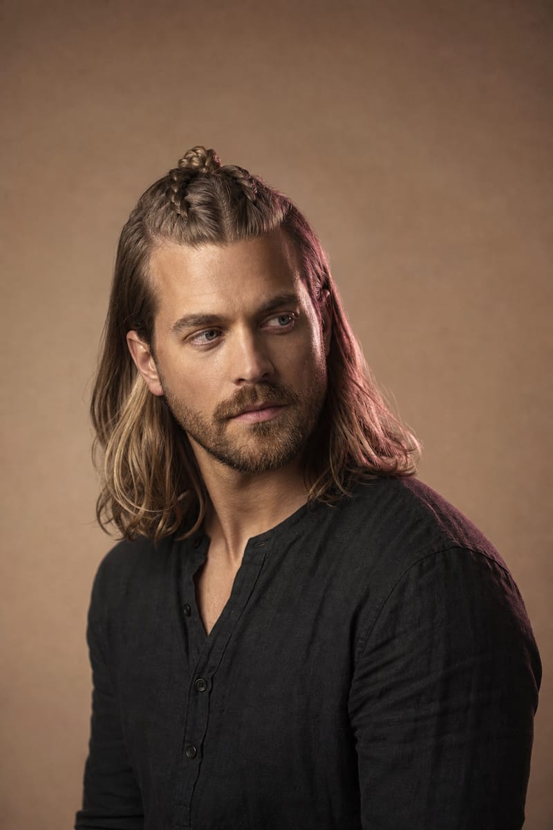 Half-up viking braids Man with long hair whose top section is braided and tied in a small knot at the crown while the rest hangs loose
