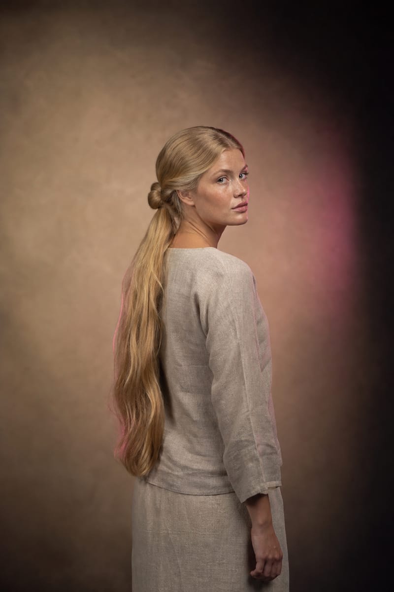 Knot with a hanging ponytail Woman seen from behind with hair parted in the middle, gathered into a knot at the back of the head and a long ponytail hanging below it